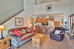 A living room with a sofa, a recliner, a wooden chest, and a kitchen in the background. - Condo 1236 at Ventana Vista (Tucson)