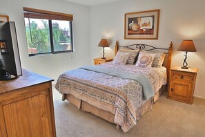 A bedroom with a bed, two bedside tables, a television, a window, and a framed picture on the wall. - Condo 1236 at Ventana Vista (Tucson)