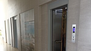 A modern elevator with a digital display, adjacent to a wall with a QR code and contact information. - Ocean View Apartment w/ Private Beach & Pools Santa Marta – Pozos Colorados (Santa Marta)