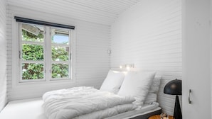 A bedroom with a bed, a nightstand, a lamp, and a window with a view of greenery. - Cozy home in Løgstrup with WiFi (Løgstrup)