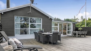 A wooden deck with outdoor furniture, a covered patio, and a large window overlooking a forested area. - Cozy home in Løgstrup with WiFi (Løgstrup)