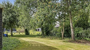A grassy outdoor area with trees and a building in the background. - Cozy home in Løgstrup with WiFi (Løgstrup)