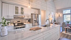 Een moderne keuken met witte kasten, roestvrijstalen apparatuur en een marmeren aanrecht.