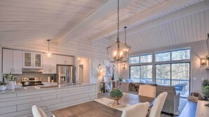 Een moderne keuken met witte kasten, een centraal eiland en een eethoek met een houten tafel en stoelen.