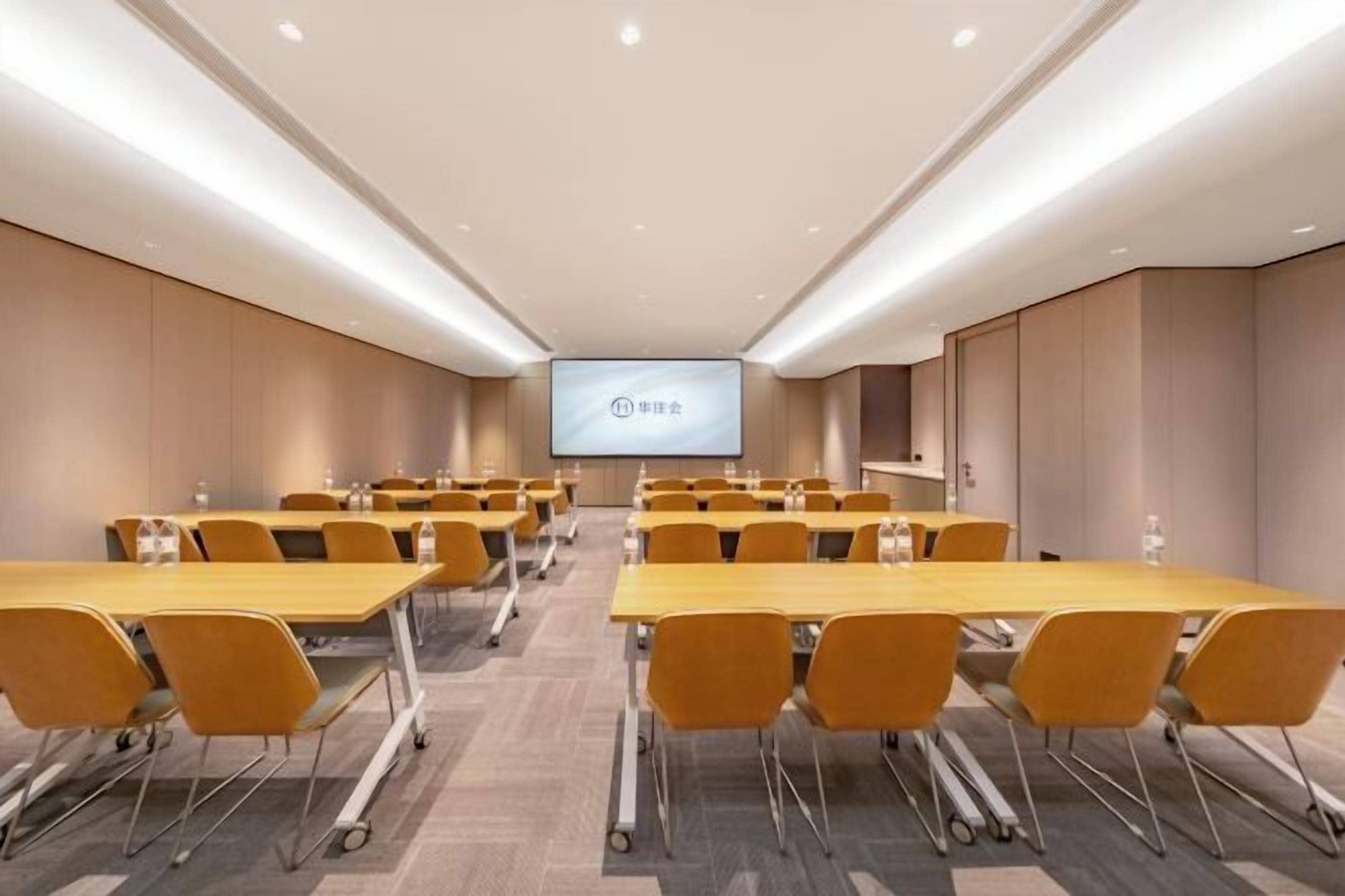 A conference room with multiple tables and chairs, a projection screen, and a neutral color scheme.