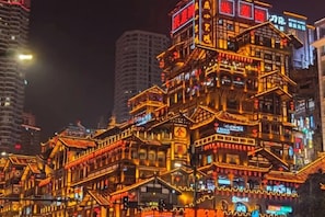 Edifício de vários andares com arquitetura tradicional, com várias varandas e sinalização iluminada.