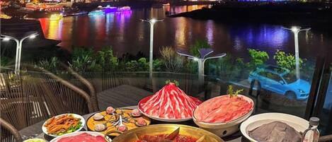 A table with various dishes and a cityscape view at night.