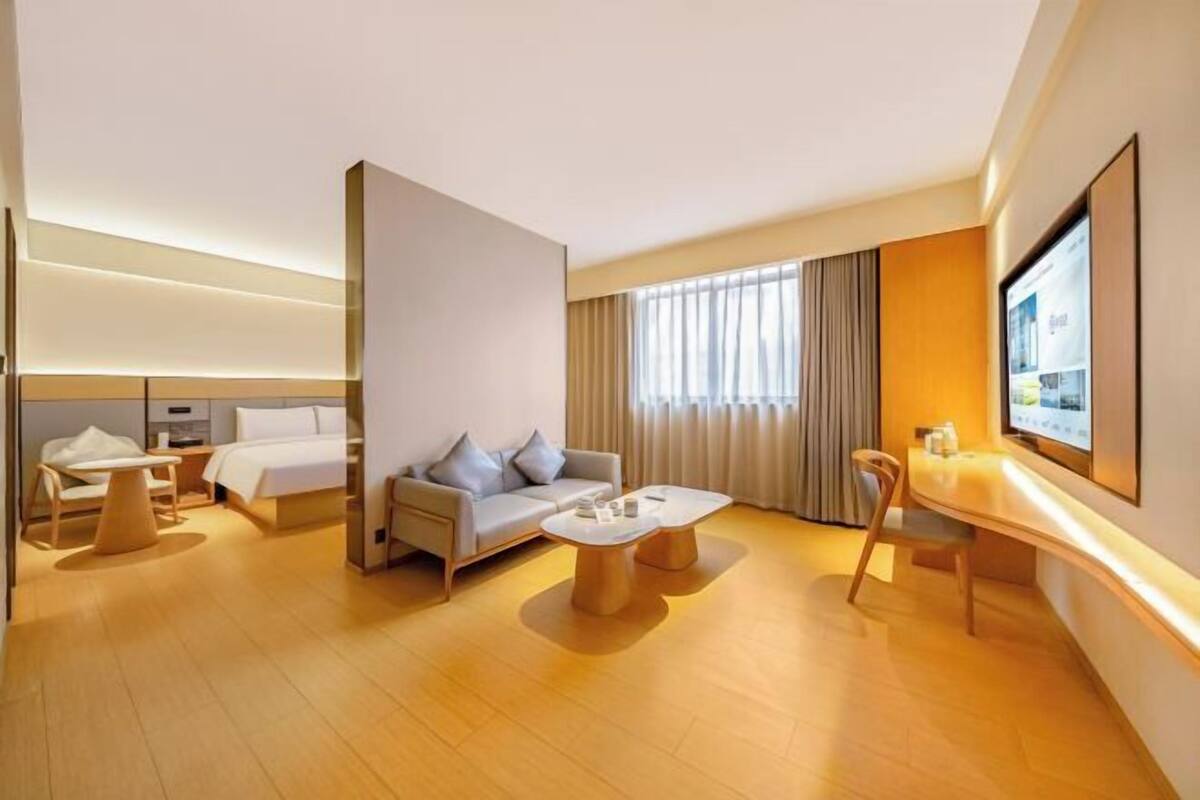 A hotel room with a bed, sofa, coffee table, TV, and a desk.