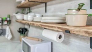 A kitchen shelf with white dishes, a roll of paper towels, and a small television. - Vineyard Ridge Farmhouse • 3BR • 2BA • Vineyard View • Fire pit • 
 (Saint James)