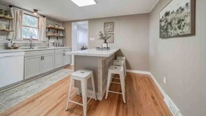 A modern kitchen with white cabinets, a central island with stools, and a skylight. - Vineyard Ridge Farmhouse • 3BR • 2BA • Vineyard View • Fire pit • 
 (Saint James)