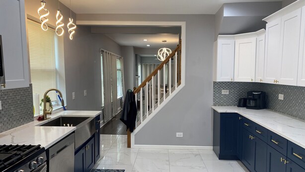 A modern kitchen with a central island, stainless steel appliances, and a staircase leading to another level. -  Charming 5 bedrooms 2 bath near Downtown Loop and Mc cormick Place, Museum  (Chicago)