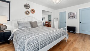 A bedroom with a white metal bed frame, patterned bedding, a chandelier, and a small table with chairs. - The Stargazer (Wimberley)