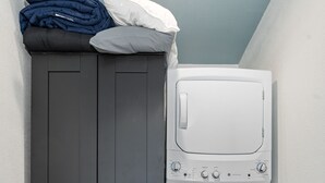 A laundry area with a dark wardrobe and a white washing machine. - The Stargazer (Wimberley)