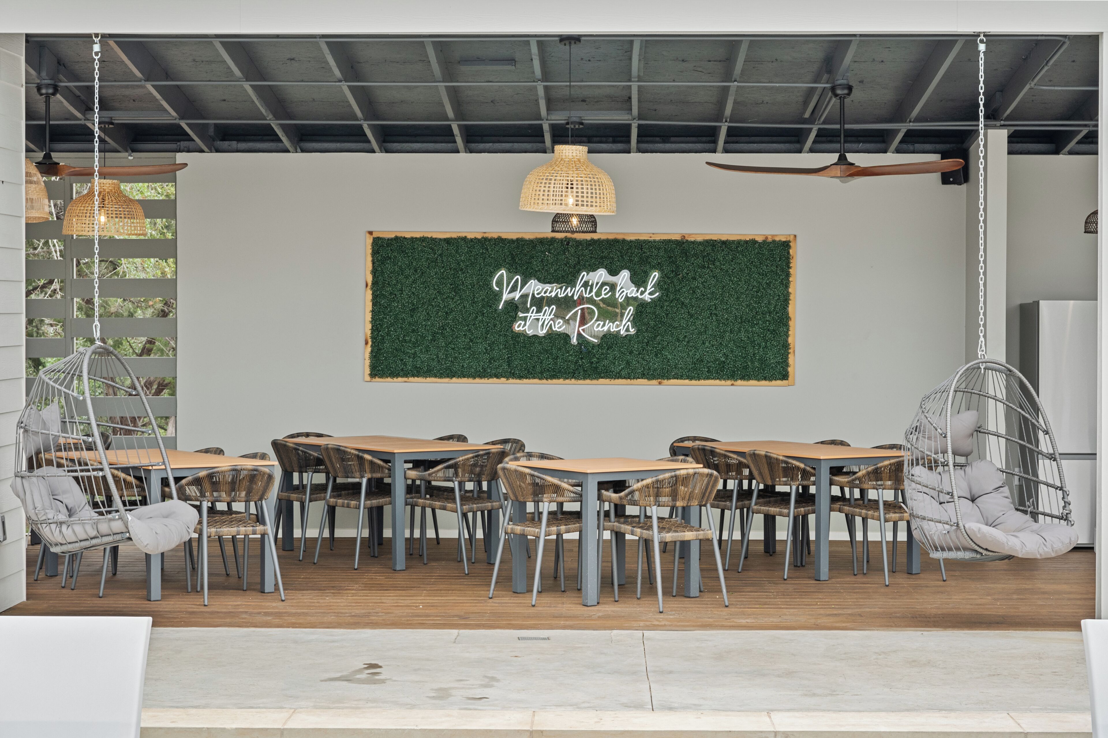 A dining area with a green wall, hanging lights, and wicker chairs.
