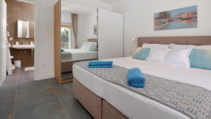 A modern hotel room with a large bed, a bathroom with a sink and mirror, and a painting on the wall. - Gorgeous home in Pasman (Pasman)