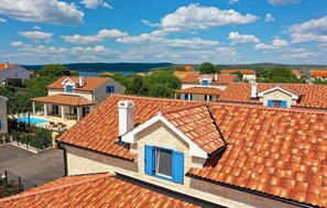 Un village côtier aux maisons aux toits de tuiles rouges, doté d’une piscine et offrant une vue dégagée sur la mer.