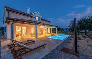 Une maison avec une piscine, un patio couvert et un jardin.