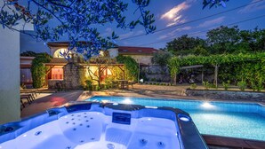 A swimming pool with hot tubs, a stone house with a red roof, and lush greenery. - Beautiful home in Rasopasno with sauna (Rasopasno)