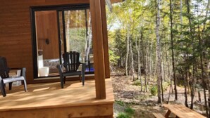 A wooden deck with two chairs and a table, overlooking a forested area.