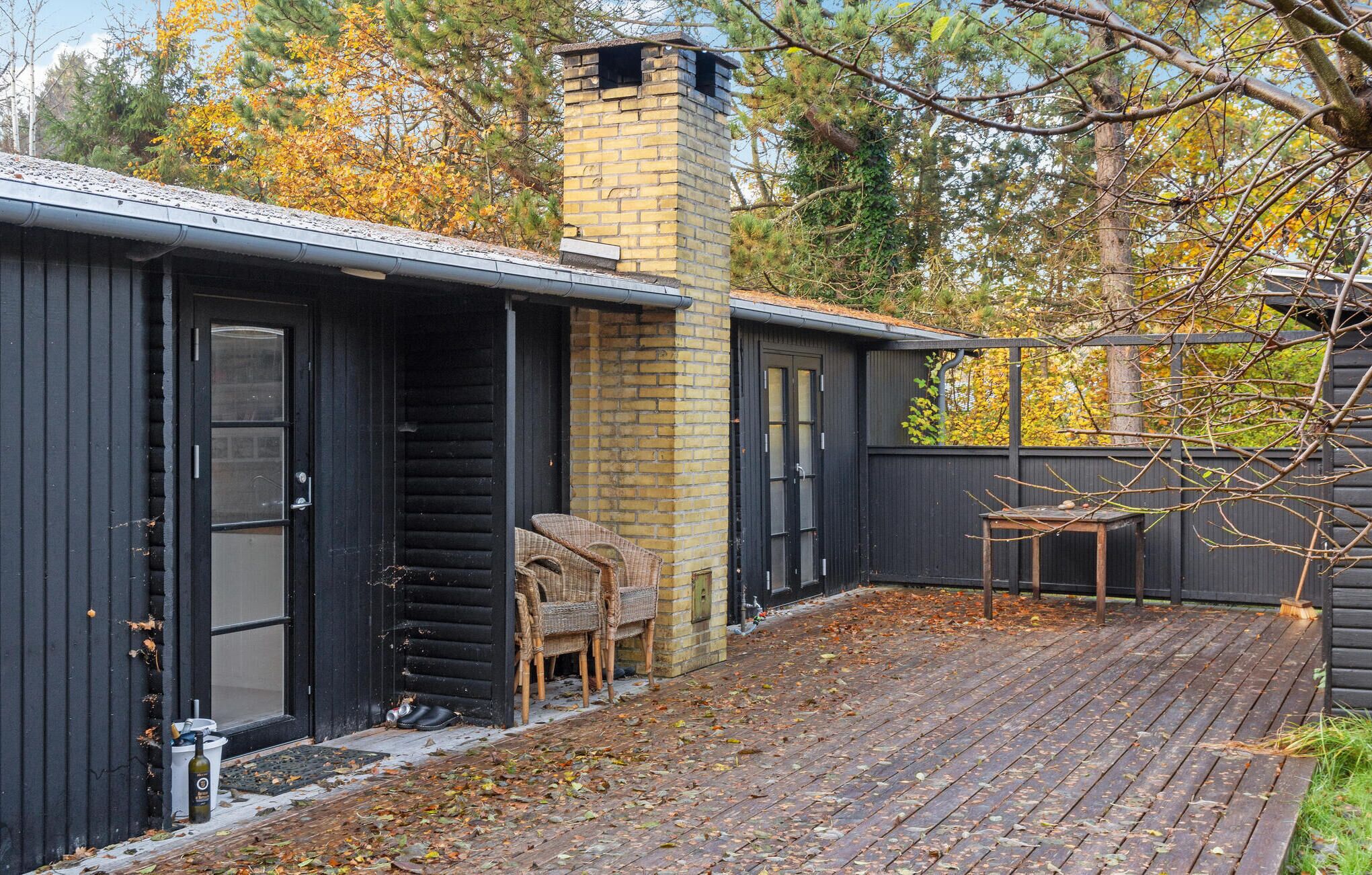 Une terrasse en bois avec une cheminée en briques, une chaise en osier et une petite table.