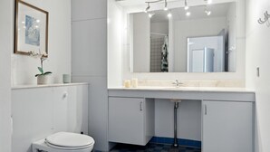 A modern bathroom with a toilet, a sink with a mirror, and a shower area.