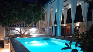 A swimming pool with a stone border, a tree, and a covered patio area with a grill. - Amazing home in Zdrelac (Zdrelac)