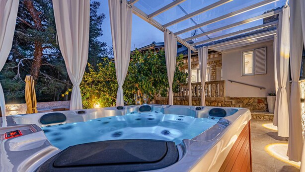 A hot tub with a glass enclosure, surrounded by curtains and a wooden deck. - Amazing home in Zdrelac (Zdrelac)