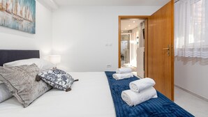 A hotel room with a bed, pillows, a blue blanket, and a wooden door. - Amazing home in Zdrelac (Zdrelac)