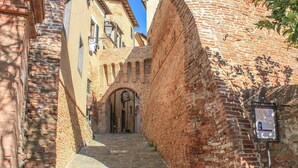 Un estrecho callejón adoquinado flanqueado por edificios históricos de ladrillo con arcos y un letrero.