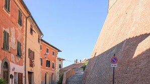 Una calle estrecha con edificios históricos, una señal de prohibido estacionar y una escalera que sube.