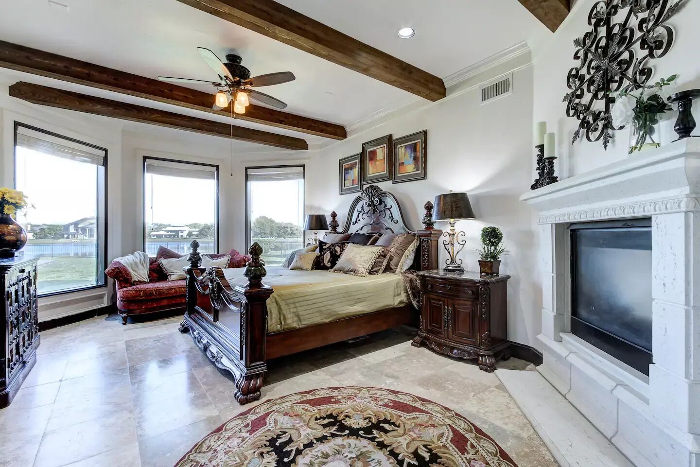 A spacious bedroom with a large bed, a fireplace, and a view of the outdoors.