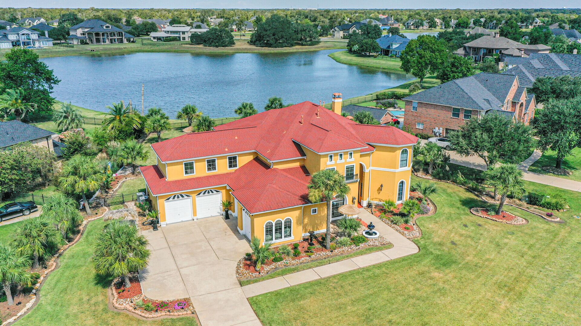 A large two-story house with a red roof, a garage, and a well-maintained lawn.