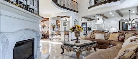 Un salón comedor espacioso con chimenea, techo alto y una escalera que sube a un nivel superior.