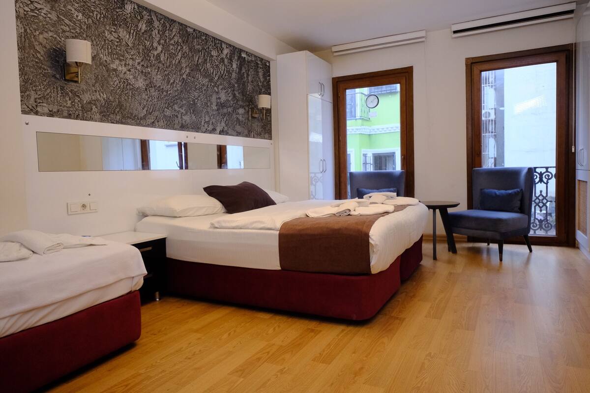 A hotel room with two beds, a balcony, and a view of the city.