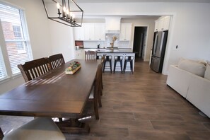 A modern kitchen with white cabinets, a wooden dining table, and a built-in island.