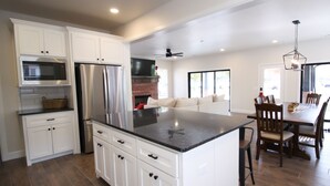 A modern kitchen with white cabinets, stainless steel appliances, and a large island. - The Campus Cottage on Elm is the ideal University of Oklahoma gameday residence (Norman)