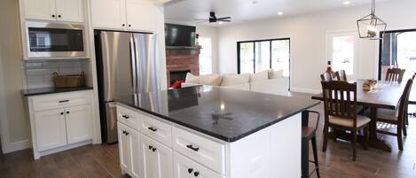 A modern kitchen with white cabinets, stainless steel appliances, and a large island.