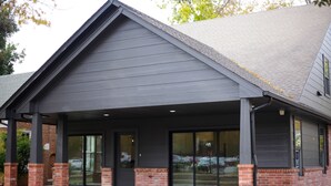 A building with a covered entrance, brick pillars, and large glass doors. - The Campus Cottage on Elm is the ideal University of Oklahoma gameday residence (Norman)