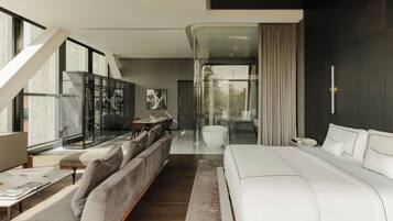 Una habitación de hotel moderna con una cama grande, un sofá, un comedor y un separador de vidrio.