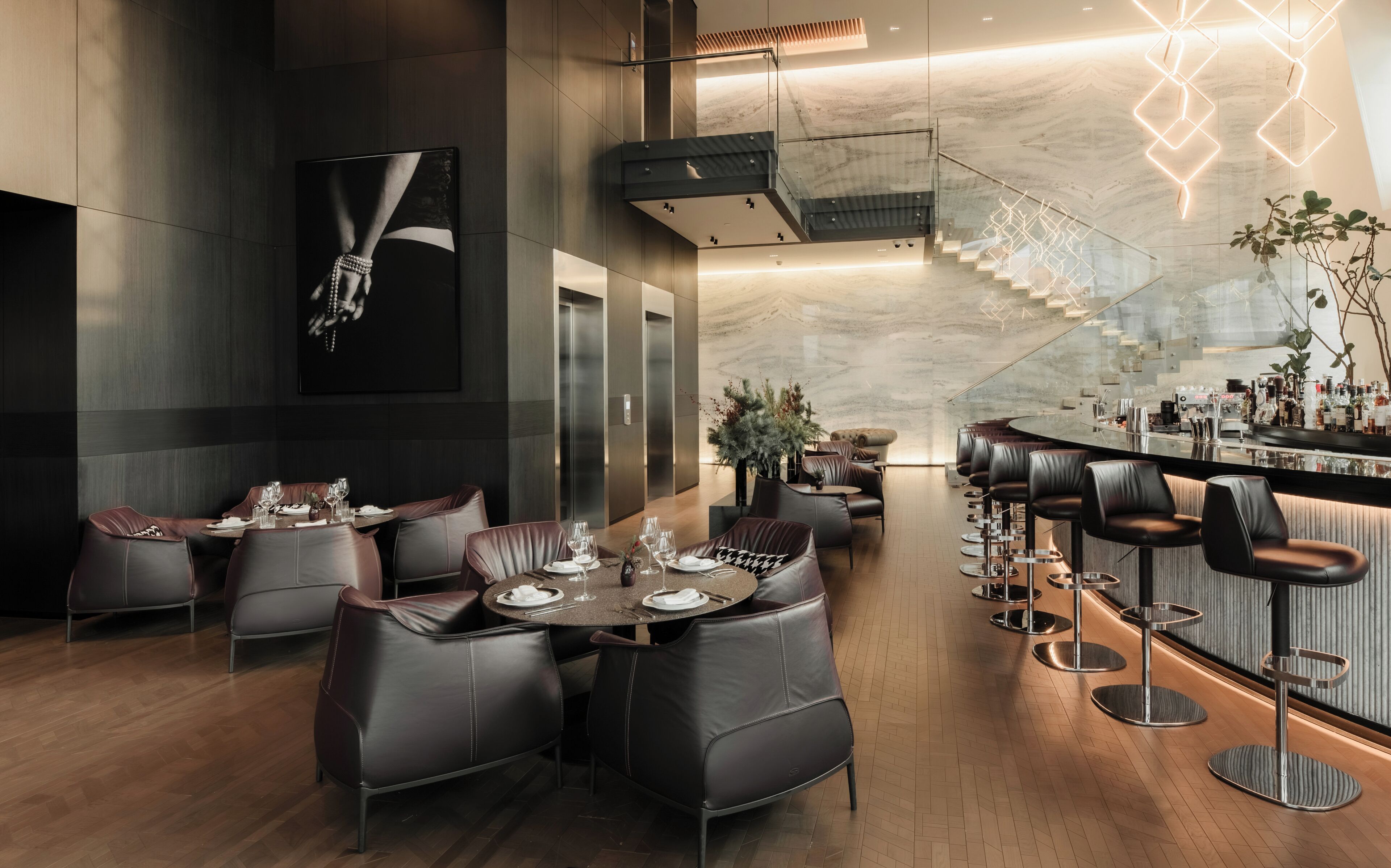 Un restaurante moderno con asientos de cuero, una zona de bar y una escalera que sube a un nivel superior.