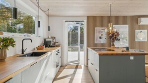 Moderni keittiö, jossa on puinen työtaso, sisäänrakennettu uuni ja suuri ikkuna.