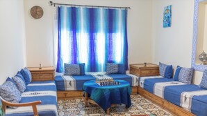 A room with a sofa set, a chess table, and a patterned rug.