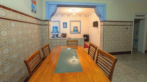 A dining area with a wooden table, chairs, patterned walls, and a ceiling with decorative moldings.
