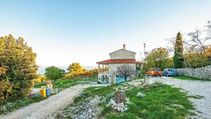 A stone house with a red-tiled roof, a small porch, and a gravel driveway. - Beautiful apartment in Gondolici (Gondolici)