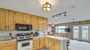 Una cocina con armarios de madera, microondas, estufa y una isla grande con pileta.