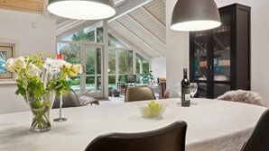 A modern dining area with a white table, clear glass vase with flowers, and a bowl of fruit. - 4 bedroom beautiful home in Melby (Melby)