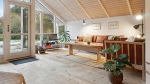 A spacious living area with a wooden ceiling, a sofa set, a coffee table, and a large window offering a view of the outdoors. - 4 bedroom beautiful home in Melby (Melby)
