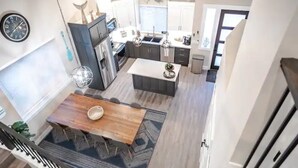Een moderne keuken met een centraal eiland, een eethoek met een houten tafel, en een trap die naar een hoger niveau leidt.
