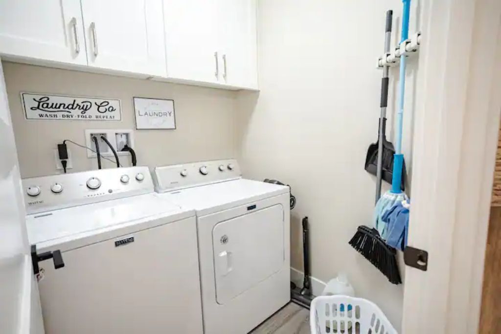 A laundry area with a washing machine, dryer, and a rack with cleaning supplies.