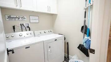 A laundry area with a washing machine, dryer, and a rack with cleaning supplies.